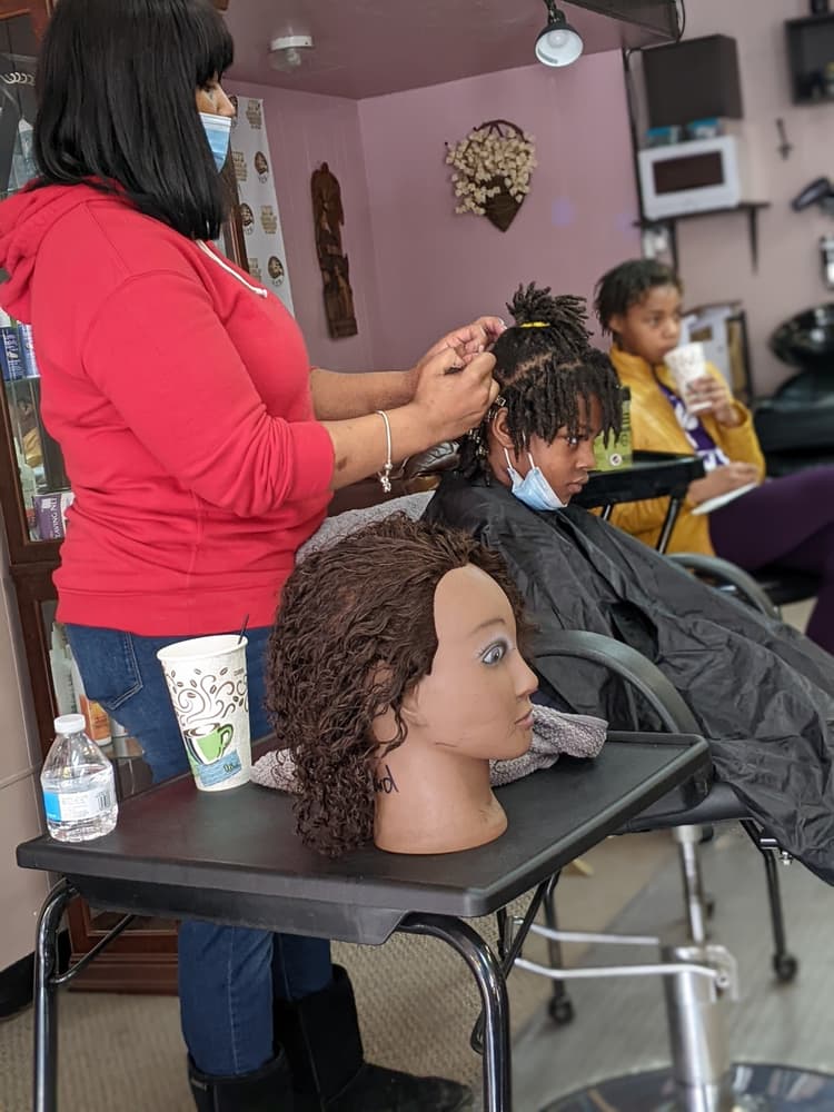 Student performing locs retwist on a client