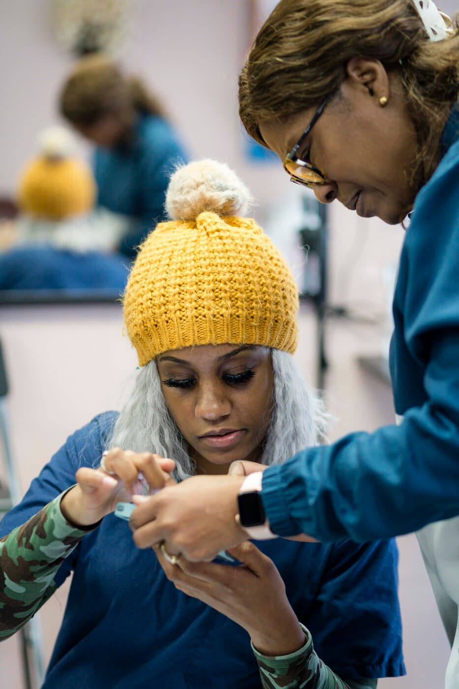 Instructor Yolande guiding a student's braiding technique one-on-one