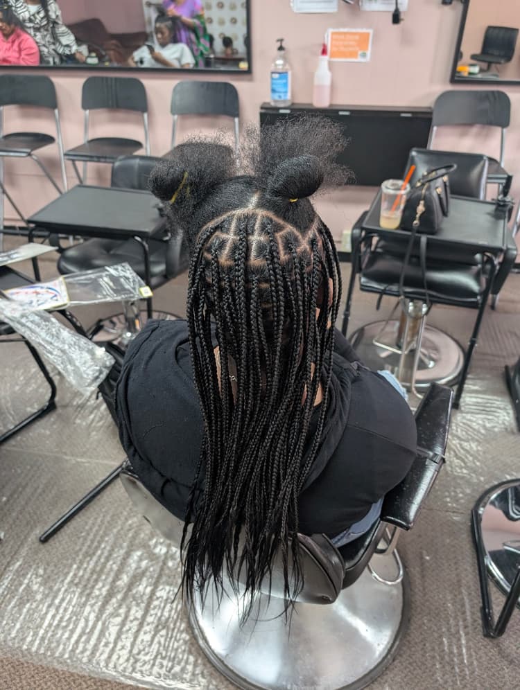 Student braiding knotless braids in classroom