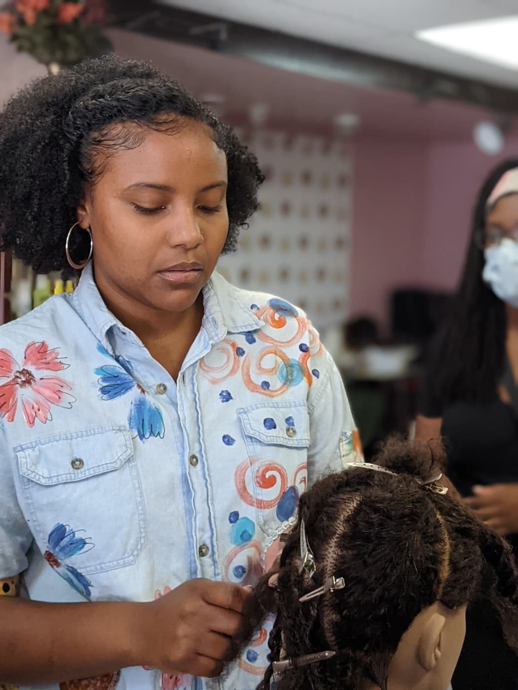 Close-up of student hands sectioning locs on a client